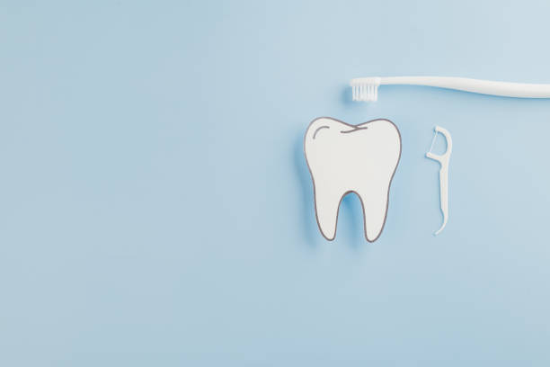 istock Dentist Day focus. A blue background featuring a paper tooth model, floss, and toothbrush 2202200916
