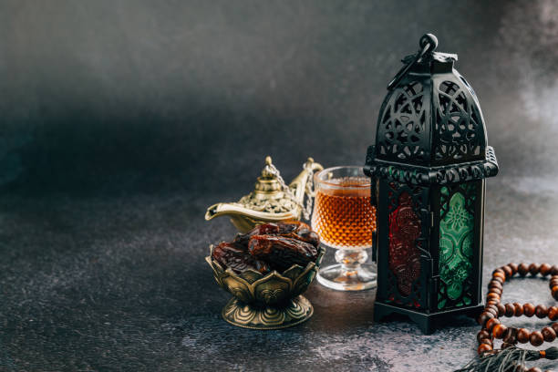istock Holy Ramadan theme featuring dates, decorative lantern, beads, and vintage lamp on dark background 2202201479