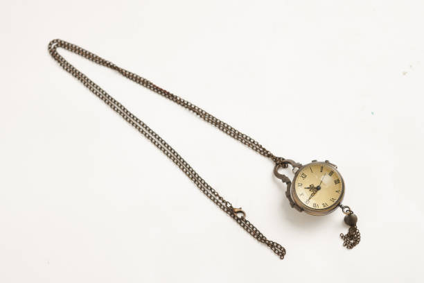 Vintage pocket watch with silver chain lying on a wooden surface