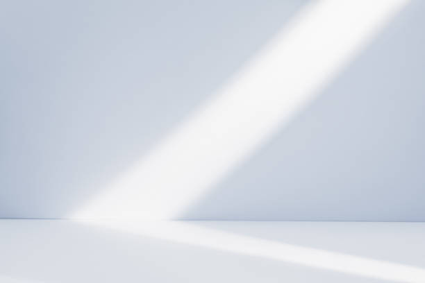 istock Bright sunlight beams illuminating a minimalistic white room background with soft shadows in the early morning 2202202307