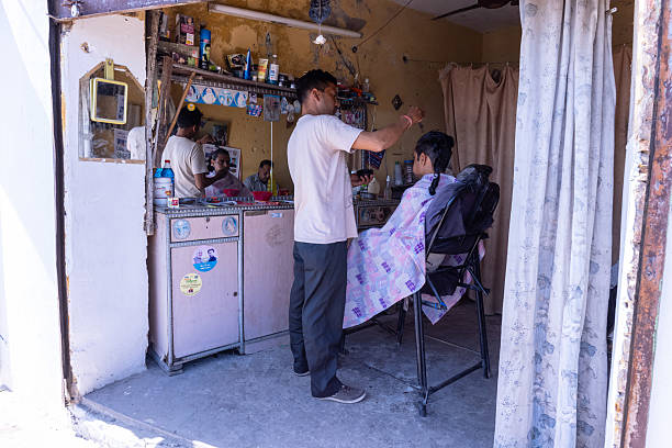 a senior barber shaving for his customer in his barber shop in melaka downtown district