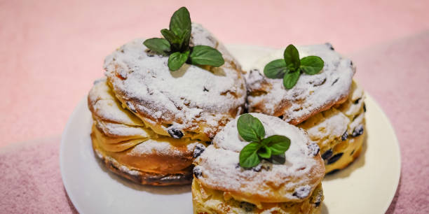 istock Eye-level shot of powdered sugar-dusted cruffins garnished with fresh mint on a white plate. 2202209281