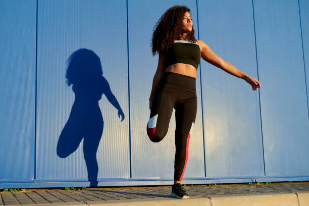 istock Woman stretching legs after running against blue wall 2202209918
