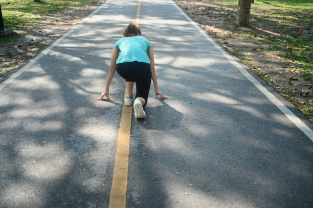 Back view portrait of beautiful young female athlete sitting, ready to run.
