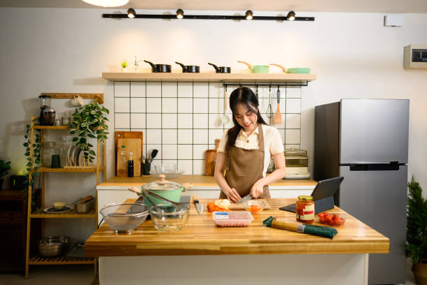 istock Smiling young woman cooking in a kitchen while preparing ingredients for spaghetti 2202210085