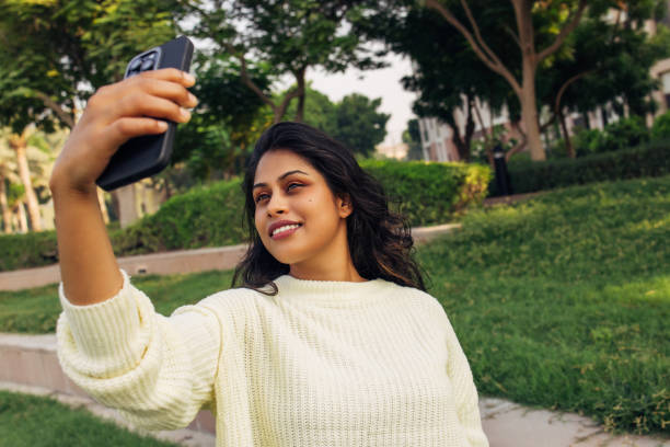 istock Young woman taking a selfie outdoors in a green park setting 2202210240