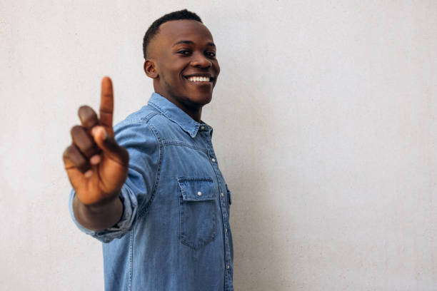 Adult Asian man wearing green shirt posing with two fingers or peace sign on white background.