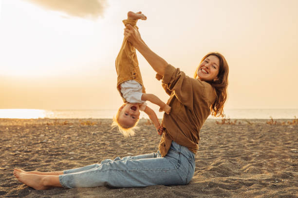 istock Mother playing with her child on the beach during a sunset 2202210693