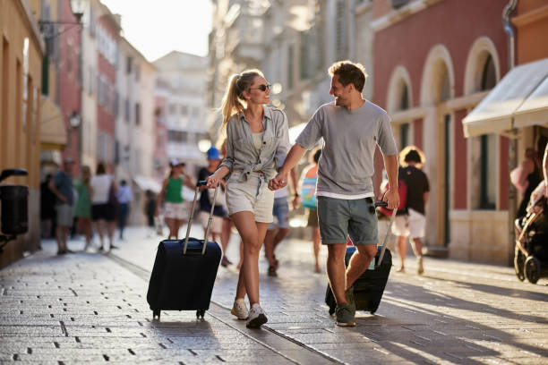 coppia felice che si tiene per mano mentre tira i bagagli per la strada della città. - croazia immagine foto e immagini stock