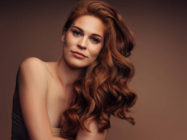 Elegant woman with wavy hair posing in soft studio lighting