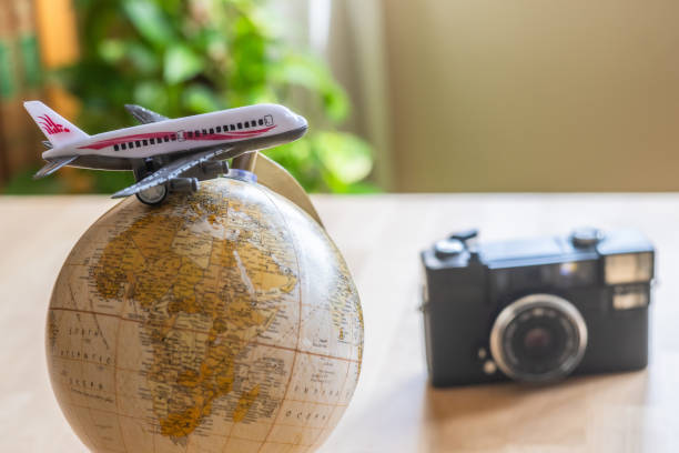 istock Miniature airplane resting on a globe alongside a vintage camera, capturing the essence of travel planning and igniting feelings of wanderlust for an upcoming world tour 2202212176