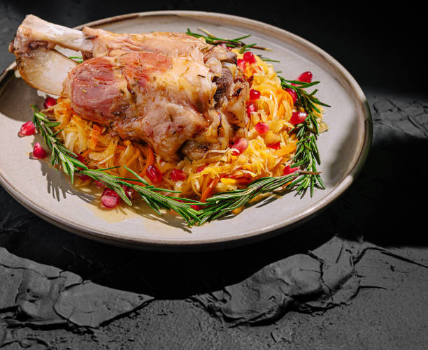 istock Savory meat dish garnished with pomegranate and herbs on a rustic plate with green foliage 2202213810