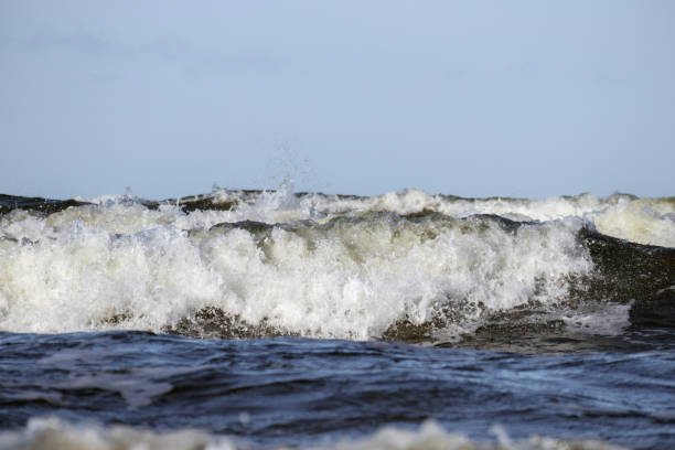 big waves crashing against the shore creating white foam.