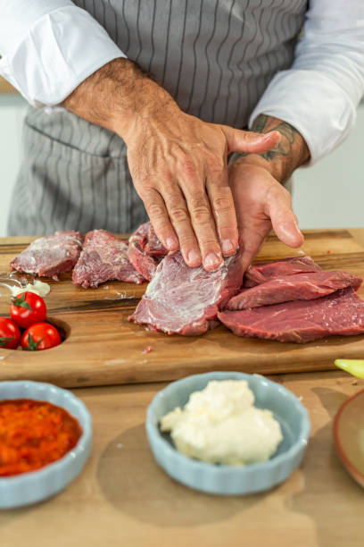 istock Chef spreading marinade on raw beef steaks for grilling or frying 2202220707