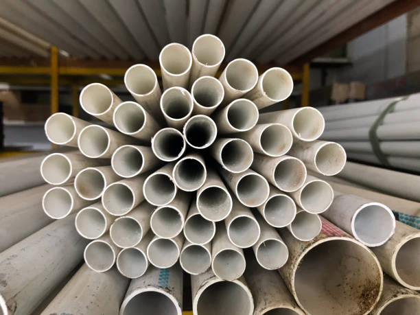 istock A neatly stacked bundle of white PVC pipes is arranged in a circular pattern, creating a symmetrical and repetitive geometric design. The pipes are stored in a warehouse with additional piping visible in the background. 2202220869