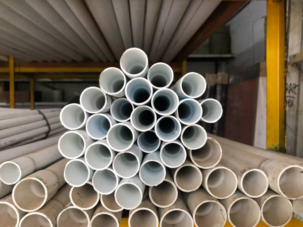 istock A stack of white PVC pipes is arranged in a circular pattern in a warehouse. The pipes vary in size, creating a symmetrical and organized structure. Yellow metal racks and additional pipes are visible in the background. 2202220929