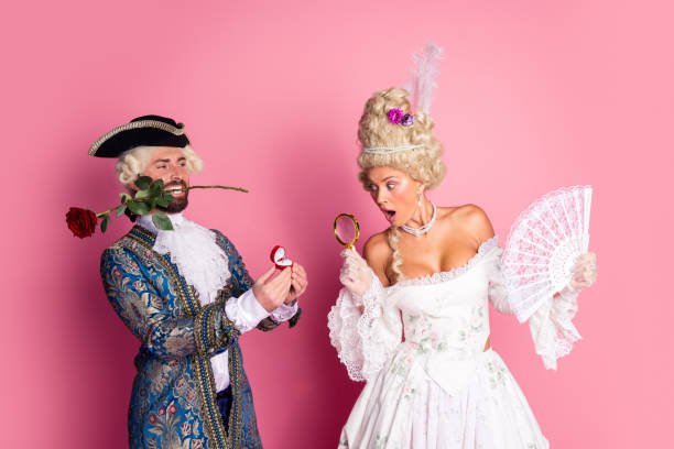 istock Amusing Romantic Couple in Historical Costumes Displaying Affection Against Pink Backdrop 2202224765