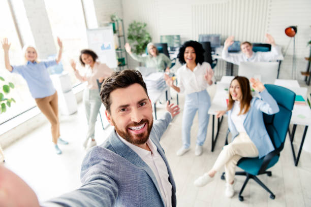 Diverse group of enthusiastic office workers cheering together in a modern workplace, capturing teamwork, energy, and collaboration