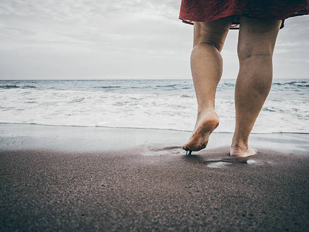 A peaceful moment captured as a person walks barefoot along the sandy beach, letting the waves gently wash over their feet, showcasing the beauty of nature and tranquility.