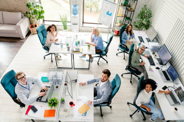 istock Diverse group of professionals collaborating in a modern office workspace with computers, top view 2202228226