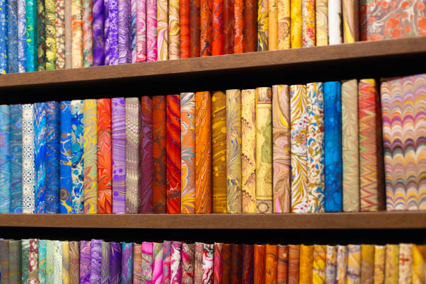Wooden shelf filled with notebooks with colorful leather covers, blue, orange, green, red, yellow. Books with colorful and patterned leather covers