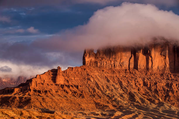 A butte in Monument Valley covered in clouds at sunset