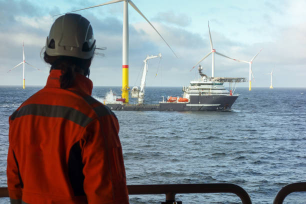 istock Offshore Wind Farm Operations – Worker Observing Service Vessels and wind farm from substation 2202232401