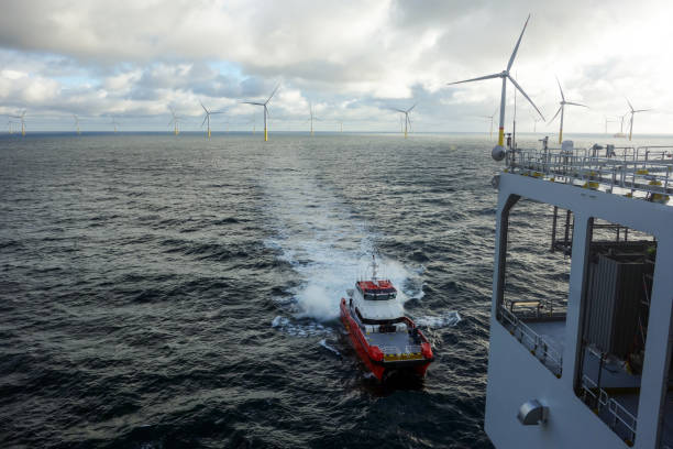 istock Offshore Wind Farm Operations - service vessel navigates through choppy waters towards an offshore substation under a cloudy sky 2202233097