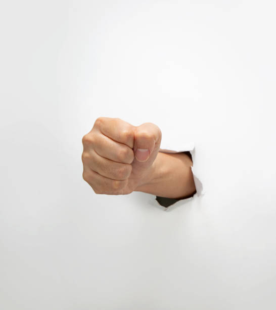 istock Fist coming out the paper hole isolated on white background 2202237298