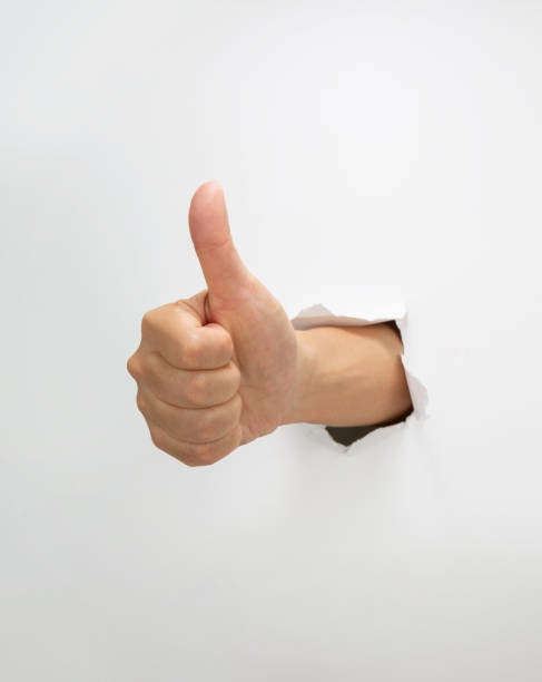 istock Thumbs up through the hole in paper sheet 2202237318