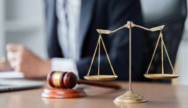 Lawyer analyzing legal documents with scales of justice and gavel on desk in modern office setting. A lawyer is focused on analyzing legal documents while scales of justice and a gavel are prominently displayed on the desk. civil rights act stock pictures, royalty-free photos & images