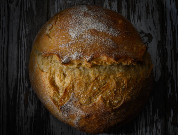 istock Golden crusted bread rests on a rustic wooden surface under soft warm lighting 2202238928