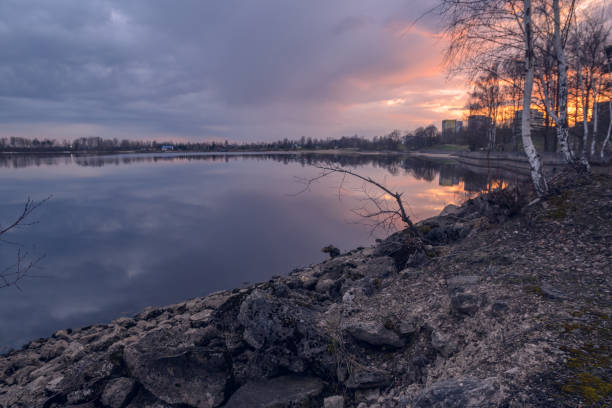 Warm hues of sunset dance on the lake's surface, while a calm shoreline invites quiet contemplation and peace.