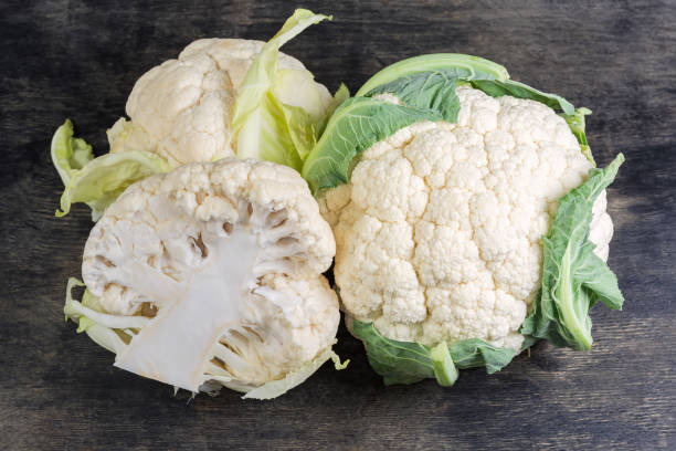 istock Half and two whole raw cauliflower heads on black surface 2202239442