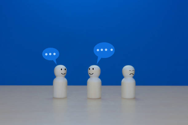 istock Gossip, Lone wooden doll leaving a group conversation 2202240484