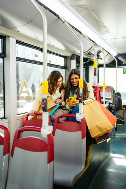 istock Two smiling women using smartphone on bus after shopping 2202242162