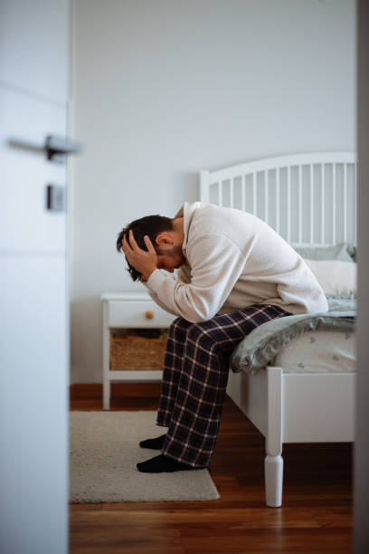 istock Man sitting on bed with head in hands 2202244228