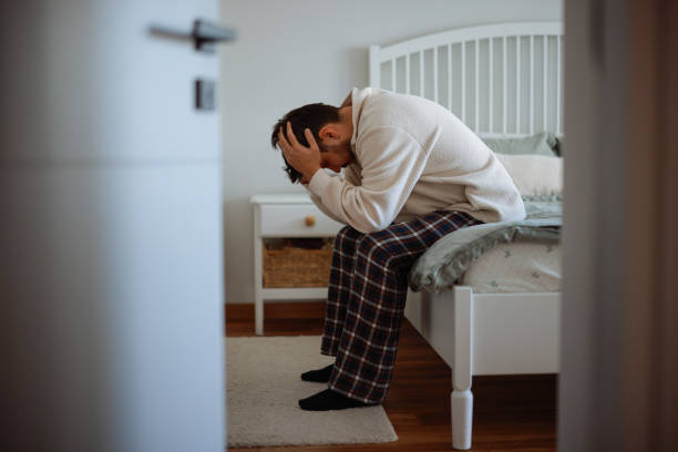 Man sitting on bed with head in hands