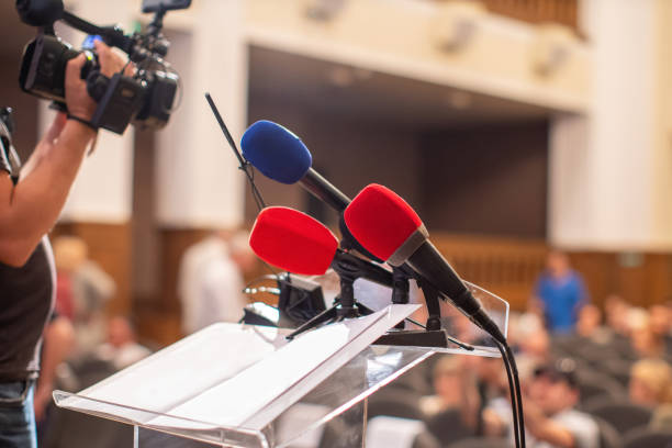 istock Microphones set up at a press conference in a large auditorium during event 2202249545