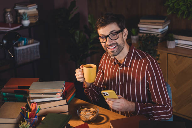 istock Young man studying at home with books and a cup of coffee in a comfortable setting, late evening study over casual preparations. 2202252157