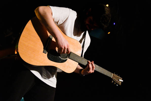 istock Acoustic Guitarist Under Spotlight – High Contrast Shadow Effect 2202255617