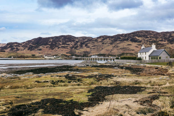 istock Beautiful Scottish landscape with coastal house and distant hills under cloudy sky 2202257662