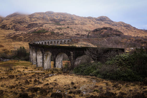 Glenfinnan Viaduct stands majestically against rolling hills, connecting scenic routes amidst Scotlands natural beauty.