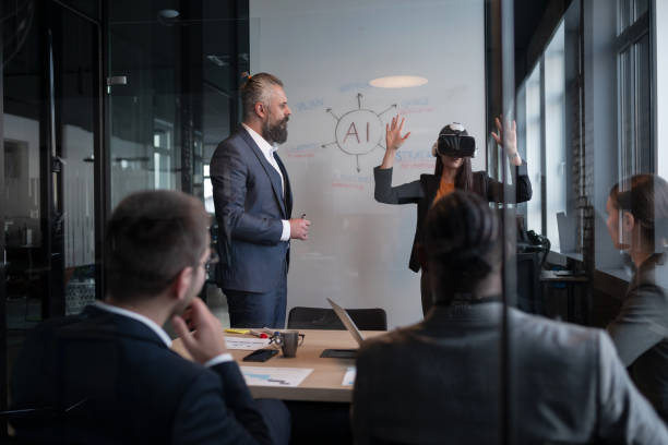 istock Business professionals in a modern office discussing artificial intelligence strategy. A woman wearing a VR headset gestures while presenting. Concept of innovation, technology, and AI integration 2202258595