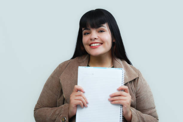 istock Happy young woman holding a notebook. Concept of writing, planning, education, creativity or study. 2202259508