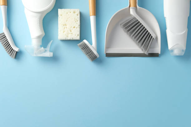 Cleaning supplies on a blue background, including brushes, a spray bottle, a sponge, and a dustpan with a brush. Ideal for illustrating cleaning, hygiene, or housekeeping themes
