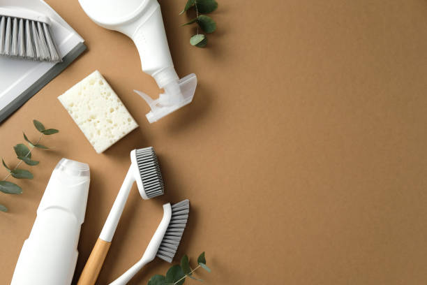 istock Eco-friendly cleaning supplies arranged on a brown background, featuring brushes, sponge, spray bottle, and eucalyptus leaves. Perfect for sustainable cleaning themes 2202260853