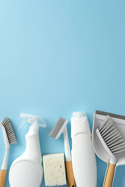 istock Flat lay cleaning tools on a blue background. Top view cleaning supplies including brushes, a spray bottle, a sponge, and a dustpan, highlighting the essentials for household cleaning tasks 2202260961