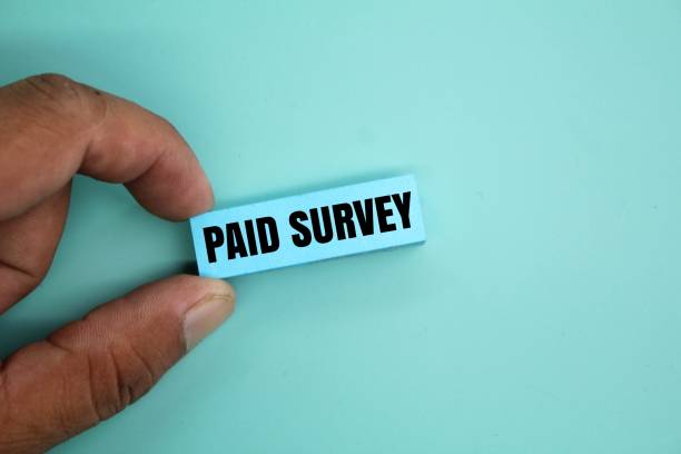 istock hand holding colored paper with the word Paid survey 2202261491