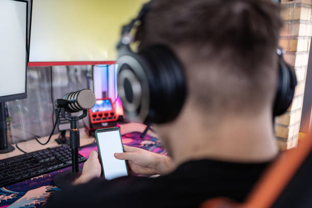 istock Anonymous gamer streaming using smartphone in gaming setup with mockup screen 2202262412
